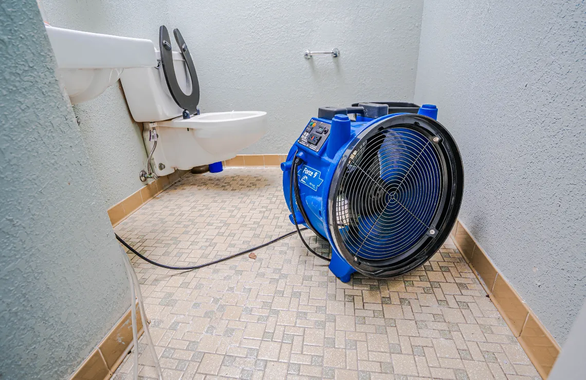 Water damage drying equipment operating in a bathroom after leak and moisture intrusion