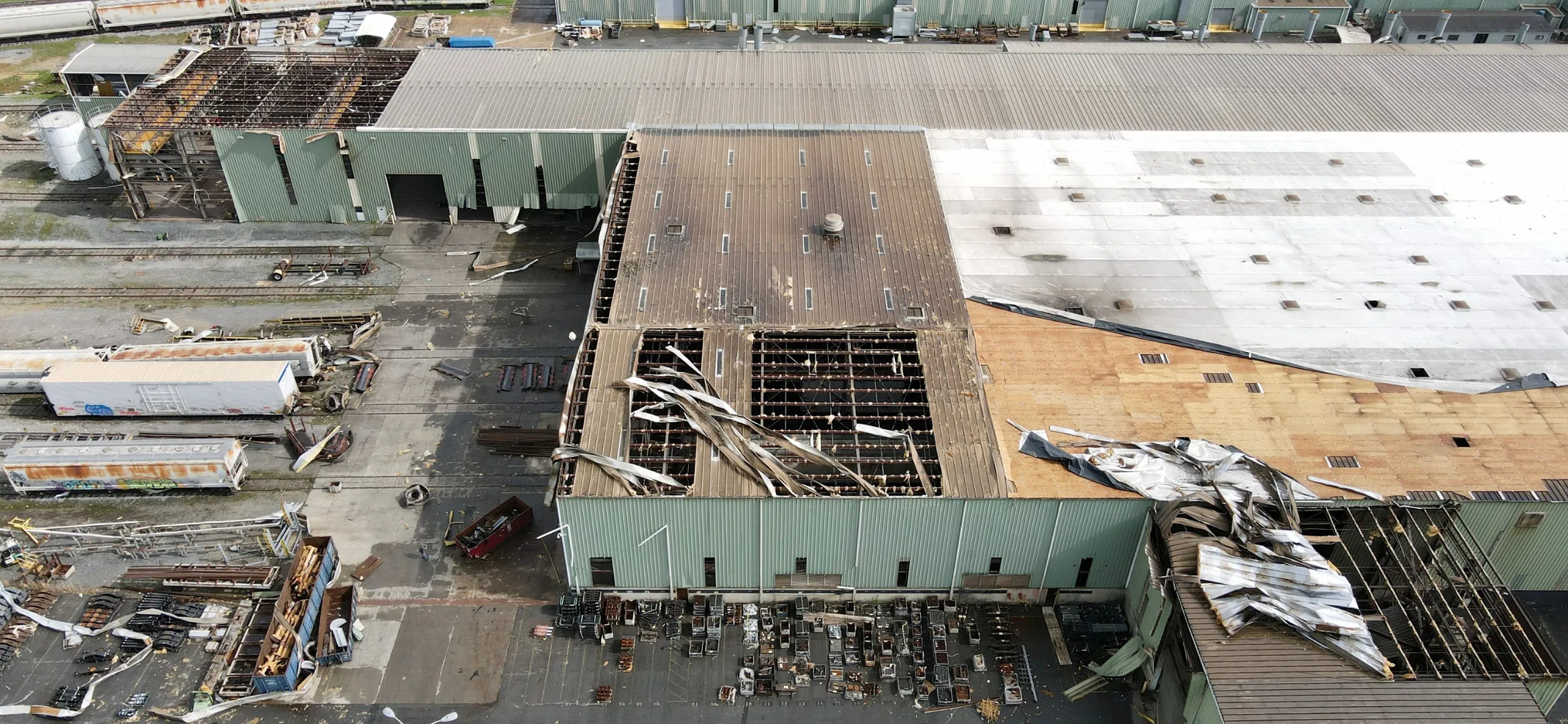 Aerial view of an industrial facility with severe roof damage requiring commercial restoration services.