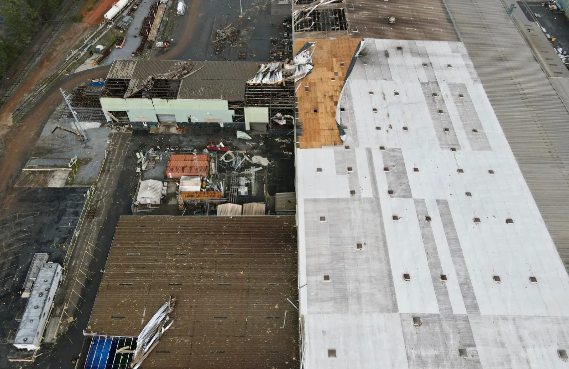 Overhead view of a damaged commercial warehouse showing extensive roof and structural failure.