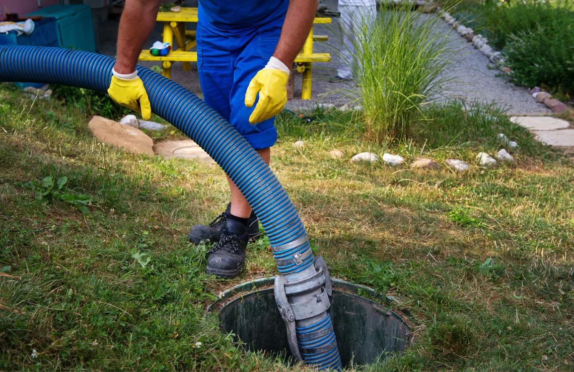 Restoration technician pumping sewage from residential manhole using professional extraction equipment
